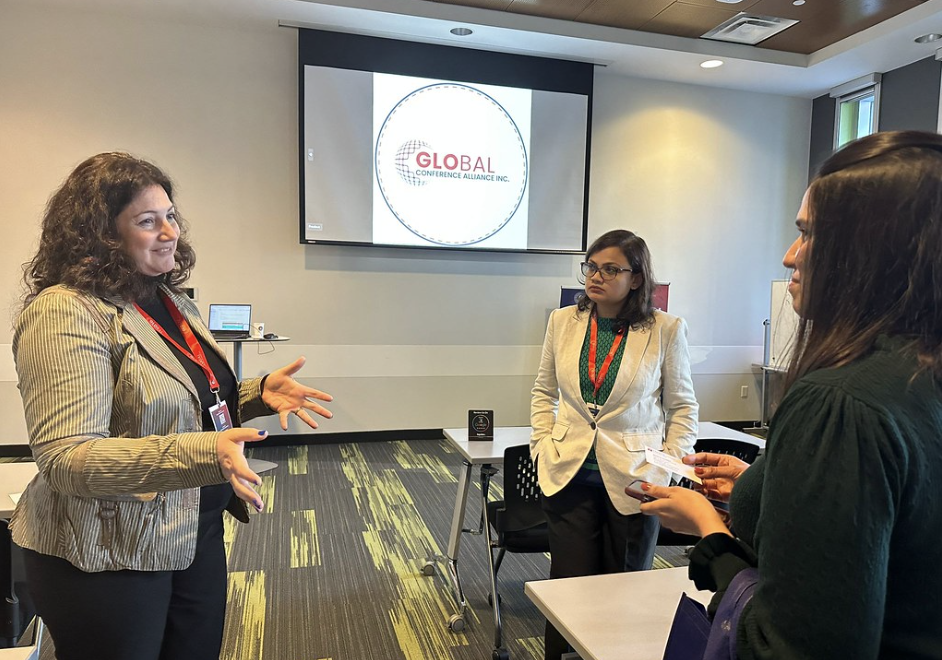 A woman discussing with two fellow conference attendees during the Global Conference event in Canada