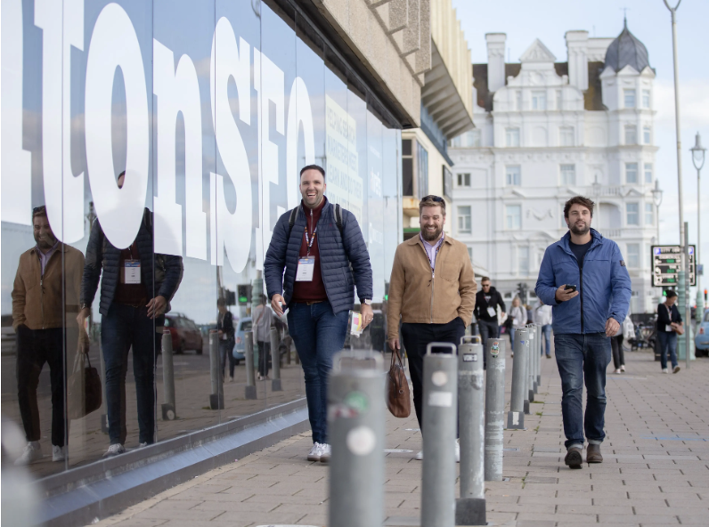 Three men walking happily on the street heading to the Brighton SEO event.