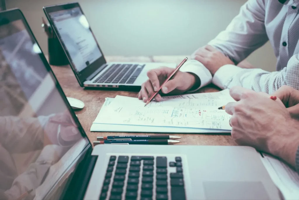 A person holding a pencil discusses his strategies with a fellow SEO professional.