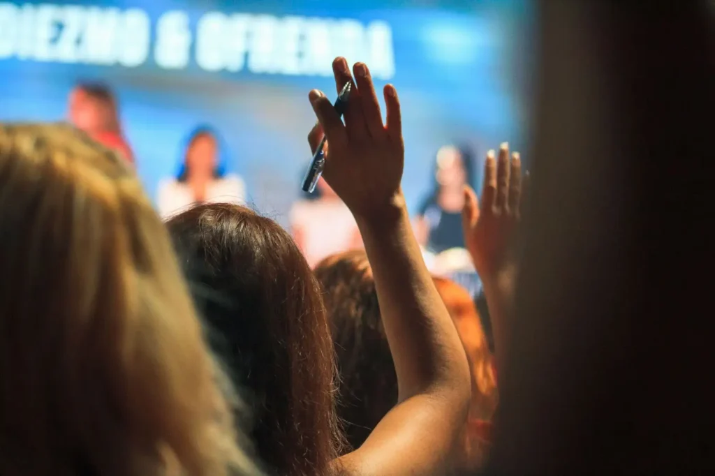 A woman raising her right hand during a conference event
